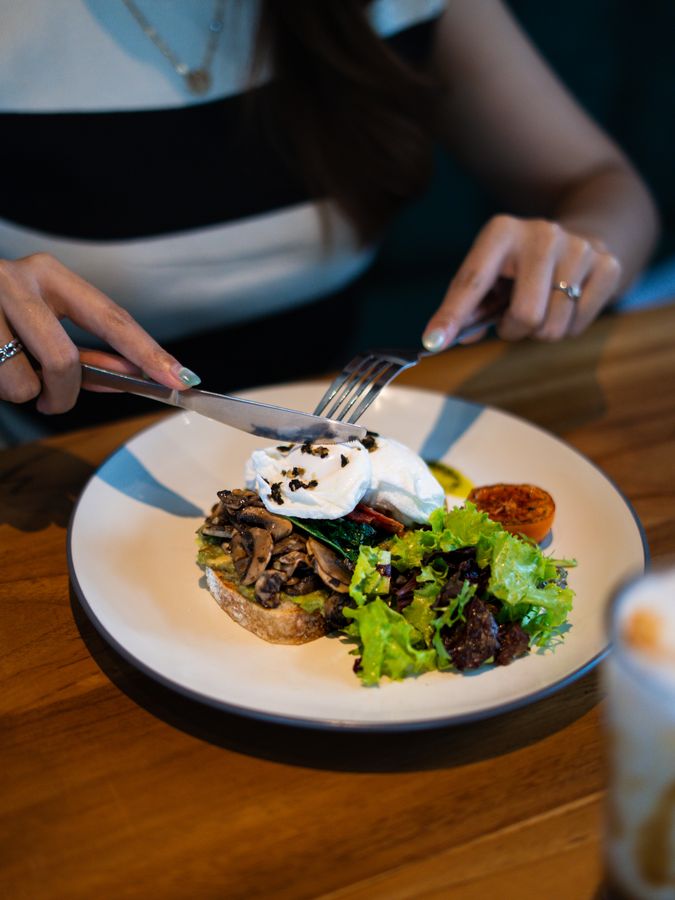 Guest dining at a wooden table at Mapogu Coffee & Eatery, Jimbaran